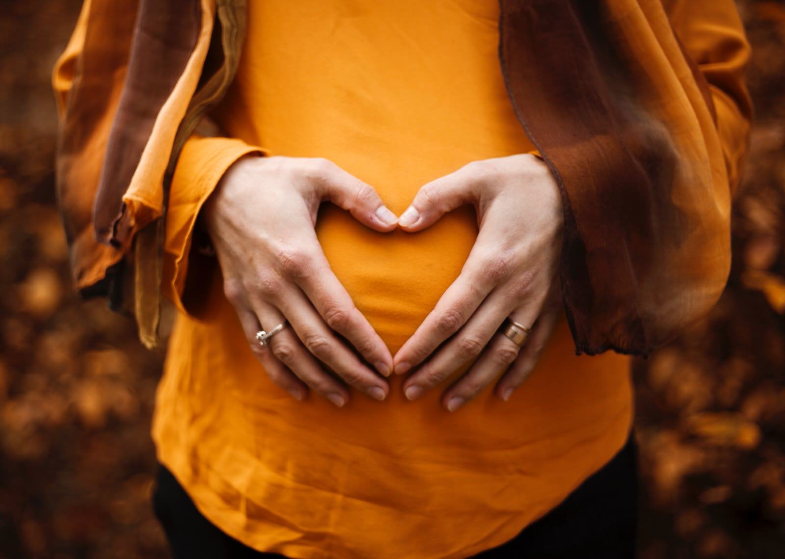 Gestante com as m&atilde;os em forma de cora&ccedil;&atilde;o sobre a barriga