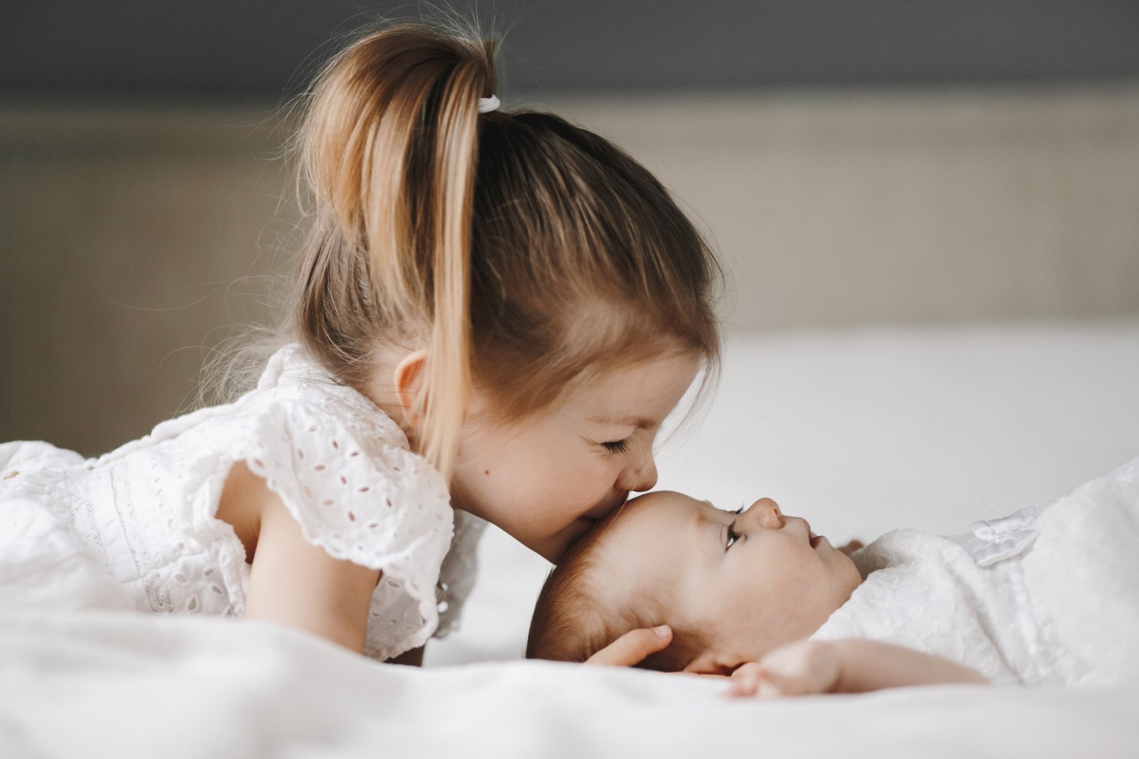 Irmã beijando a testa do bebê recém-nascido